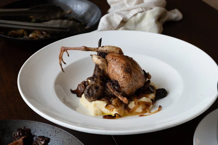 A roast woodcock sitting on a white plate in an elegant restaurant.