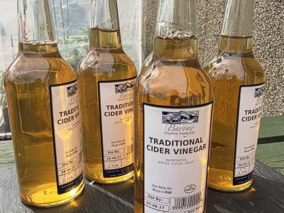 4 bottles of apple cider vinegar sitting on a slate.