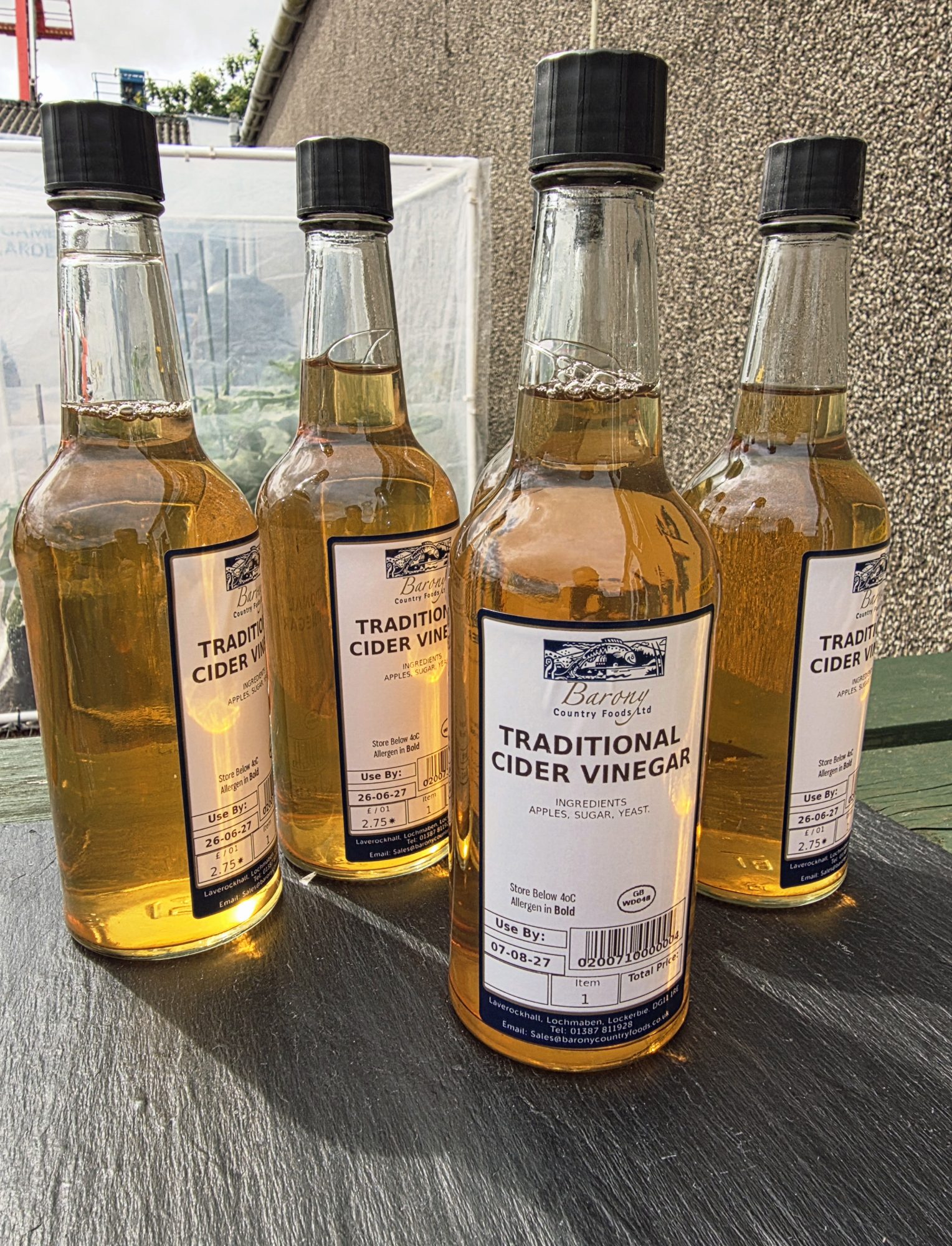 4 bottles of apple cider vinegar sitting on a slate.
